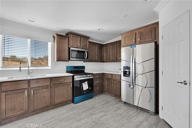 kitchen featuring sink, stainless steel appliances, dark brown cabinets, and light hardwood / wood-style floors