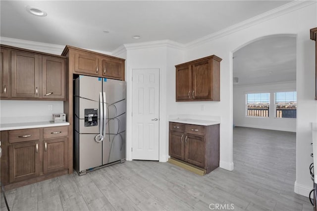 kitchen featuring stainless steel fridge, light hardwood / wood-style floors, dark brown cabinets, and crown molding