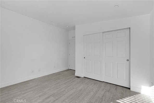 unfurnished bedroom featuring a closet and light wood-type flooring