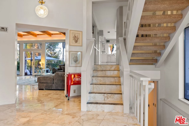 stairway with beam ceiling and french doors