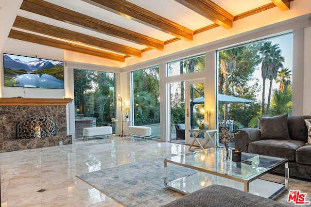 sunroom / solarium featuring beam ceiling and a stone fireplace