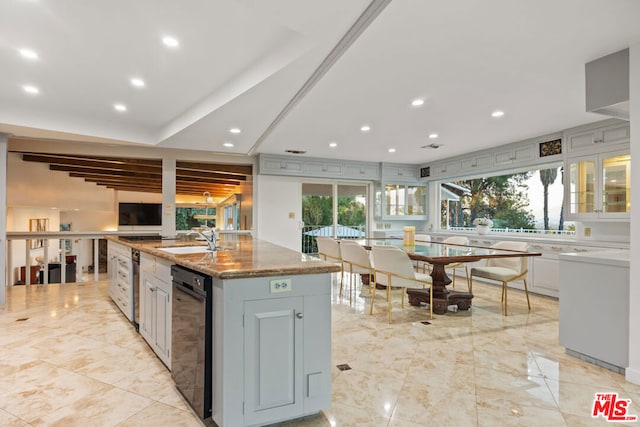 kitchen featuring sink, light stone counters, plenty of natural light, gray cabinets, and a center island with sink