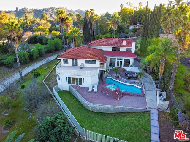 rear view of house featuring a mountain view, a yard, a fenced in pool, and a patio area