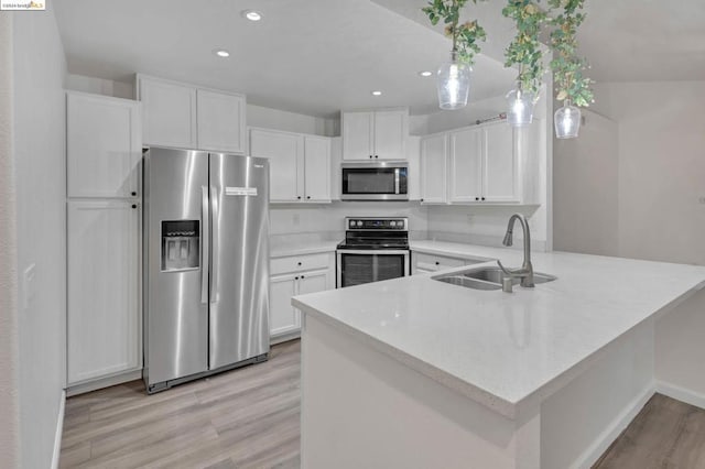 kitchen featuring sink, white cabinetry, light hardwood / wood-style flooring, kitchen peninsula, and stainless steel appliances