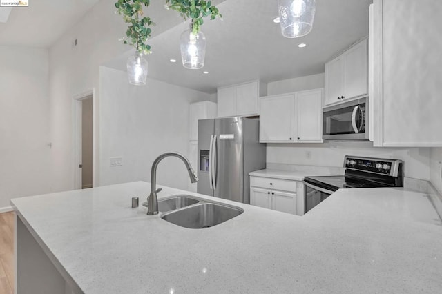 kitchen with sink, white cabinetry, appliances with stainless steel finishes, kitchen peninsula, and pendant lighting