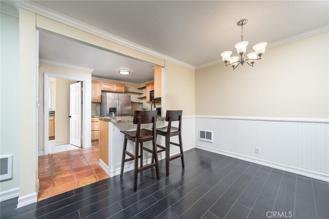 kitchen with pendant lighting, stainless steel refrigerator with ice dispenser, light brown cabinets, kitchen peninsula, and crown molding