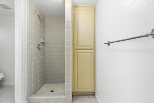 bathroom featuring a tile shower, toilet, and tile patterned floors