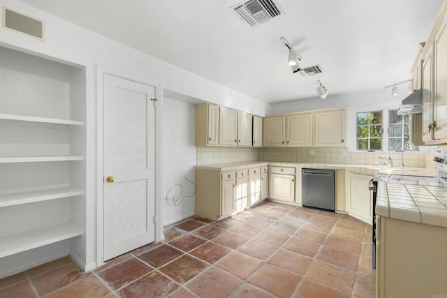 kitchen with tile counters, dishwasher, rail lighting, tasteful backsplash, and cream cabinets