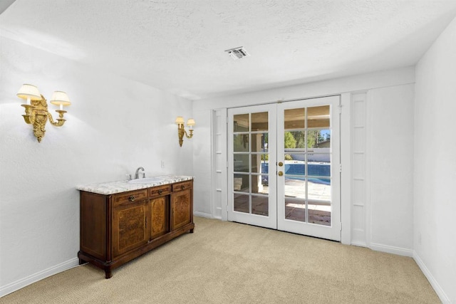 entryway featuring french doors, a textured ceiling, light colored carpet, and sink