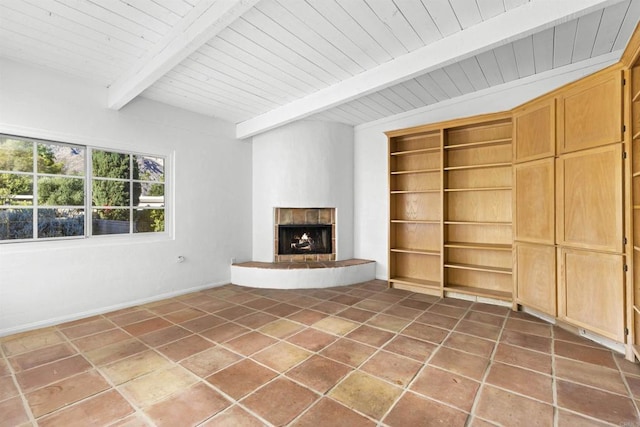 unfurnished living room featuring beam ceiling, wooden ceiling, a fireplace, and built in features