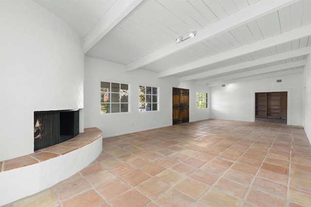 unfurnished living room featuring a fireplace, beam ceiling, and light tile patterned flooring