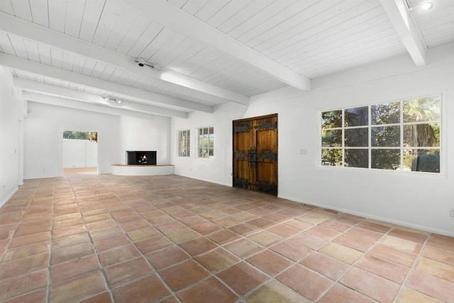 unfurnished living room with beamed ceiling, tile patterned floors, and a healthy amount of sunlight