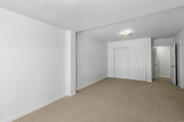 unfurnished bedroom featuring light colored carpet and a closet