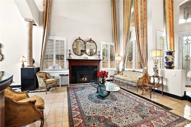 sitting room featuring light tile patterned floors, decorative columns, and a high ceiling