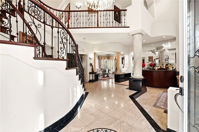 entryway featuring an inviting chandelier, a towering ceiling, and decorative columns