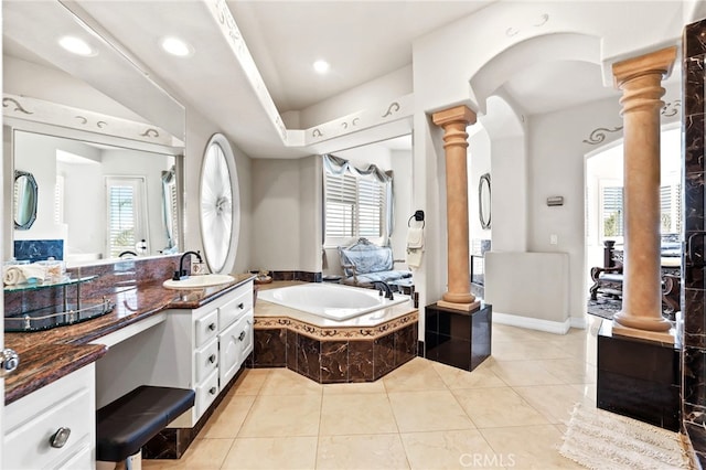 bathroom featuring a relaxing tiled tub, tile patterned floors, vanity, and ornate columns