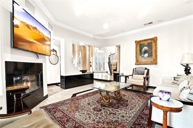 sitting room with light tile patterned floors, crown molding, decorative columns, and a tile fireplace