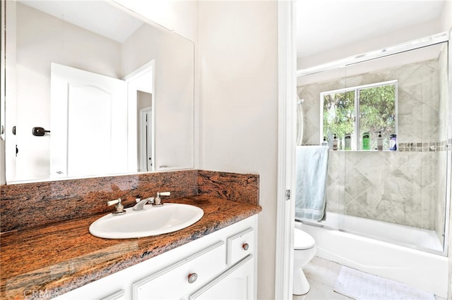 full bathroom featuring vanity, combined bath / shower with glass door, and toilet