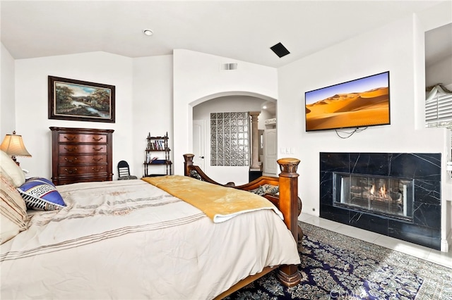 bedroom featuring tile patterned flooring, a high end fireplace, and vaulted ceiling