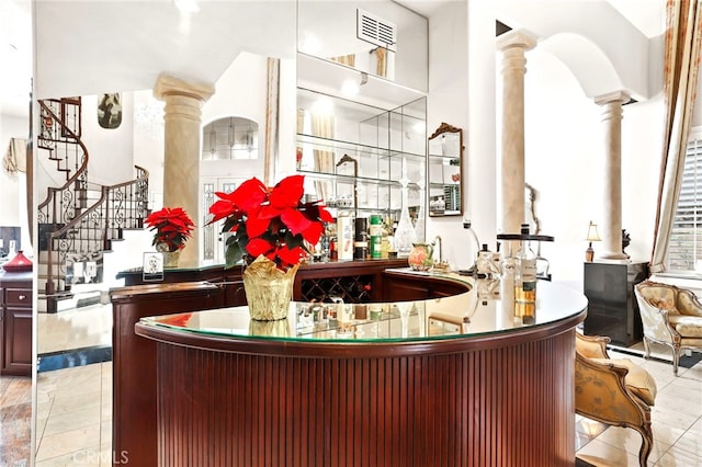 bar featuring decorative columns and light tile patterned floors