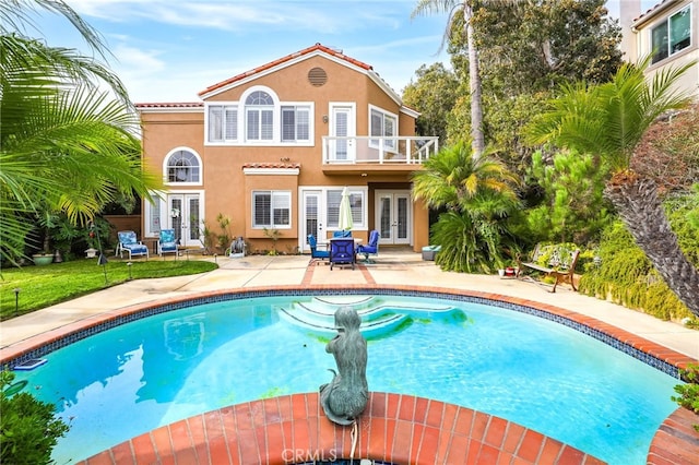 back of house featuring french doors, a balcony, and a patio area