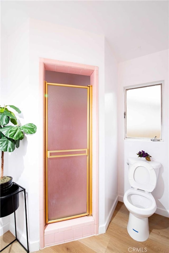 bathroom with toilet, an enclosed shower, and wood-type flooring