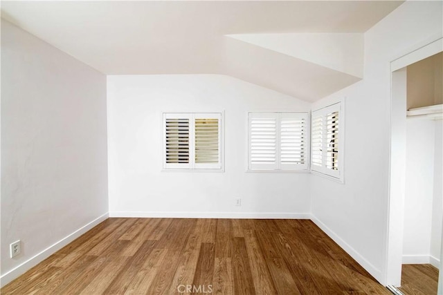 spare room featuring hardwood / wood-style floors and vaulted ceiling