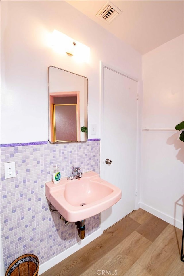 bathroom with hardwood / wood-style floors, tile walls, and sink