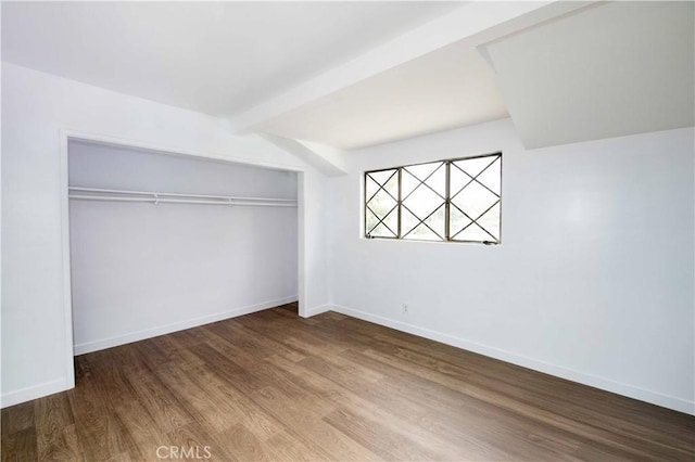 unfurnished bedroom featuring hardwood / wood-style floors, a closet, and beam ceiling