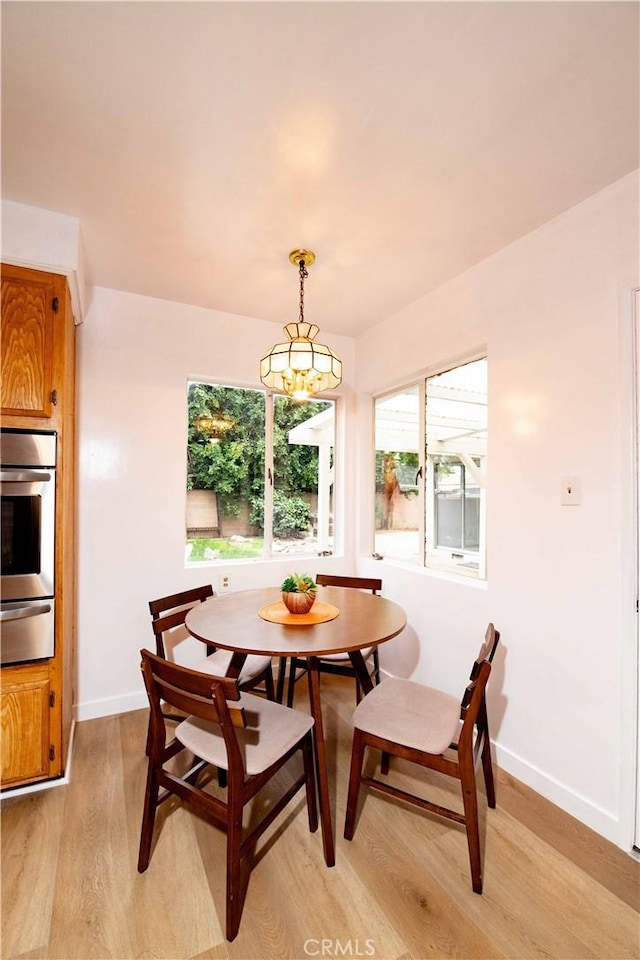 dining space with light hardwood / wood-style flooring and a notable chandelier