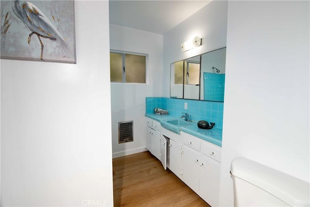 bathroom featuring hardwood / wood-style floors, decorative backsplash, toilet, and vanity