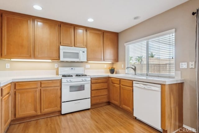 kitchen featuring white appliances, sink, and light wood-type flooring