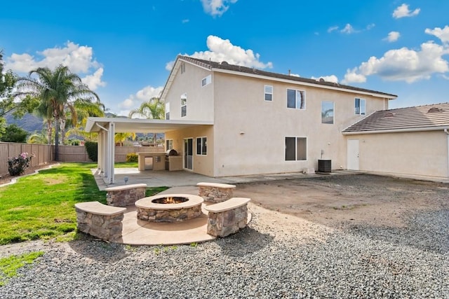 rear view of house with exterior kitchen, a patio, cooling unit, and a fire pit