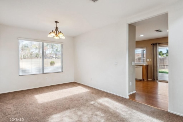 carpeted spare room with a chandelier