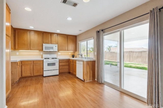 kitchen featuring white appliances, sink, and light hardwood / wood-style floors