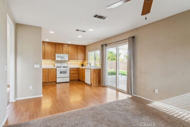 kitchen featuring light carpet, sink, white appliances, and ceiling fan