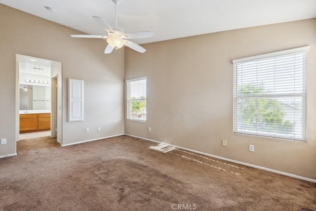 unfurnished bedroom with ceiling fan, ensuite bath, carpet, and a high ceiling