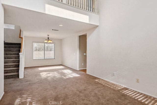 unfurnished living room featuring a notable chandelier, a high ceiling, and carpet