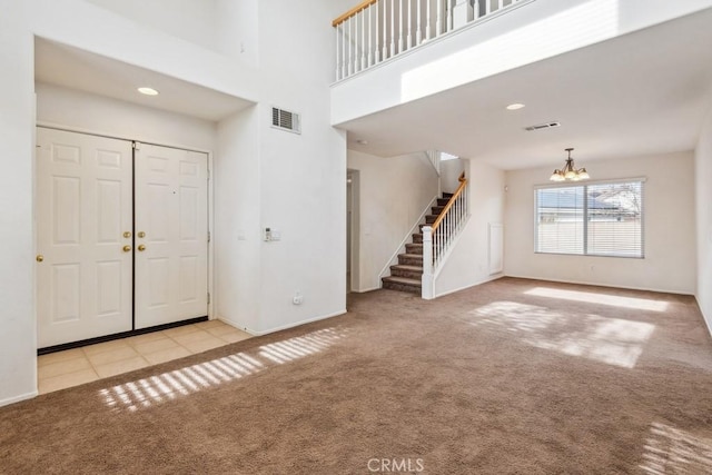 carpeted foyer with a towering ceiling and a chandelier