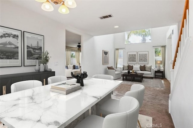 dining room with carpet flooring and ceiling fan with notable chandelier