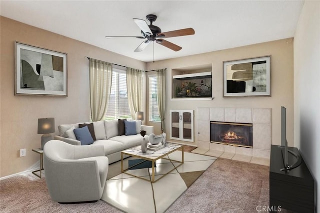 living room featuring ceiling fan, a tiled fireplace, and carpet floors