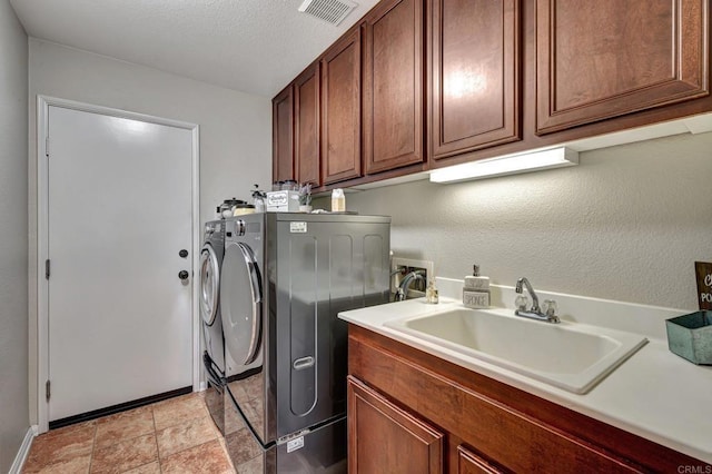 clothes washing area featuring a textured ceiling, cabinets, sink, and washing machine and clothes dryer