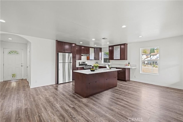 kitchen featuring stainless steel appliances, a center island, hardwood / wood-style floors, and dark brown cabinets