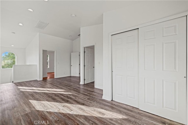 unfurnished bedroom with hardwood / wood-style floors, a closet, and lofted ceiling