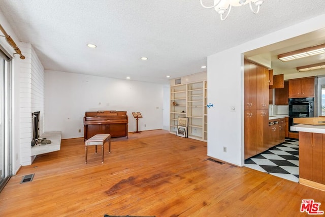 misc room featuring a textured ceiling, a fireplace, and light hardwood / wood-style flooring