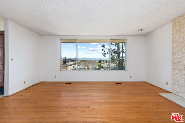 empty room featuring a textured ceiling and light wood-type flooring