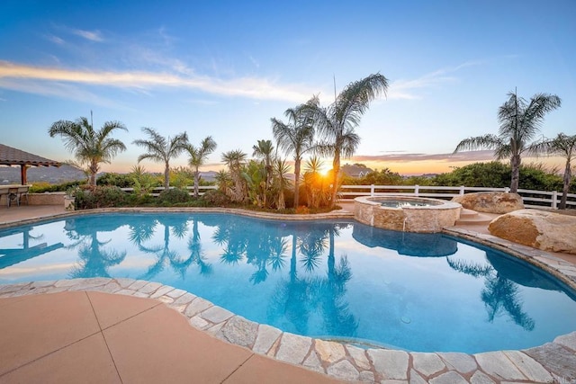 pool at dusk with an in ground hot tub