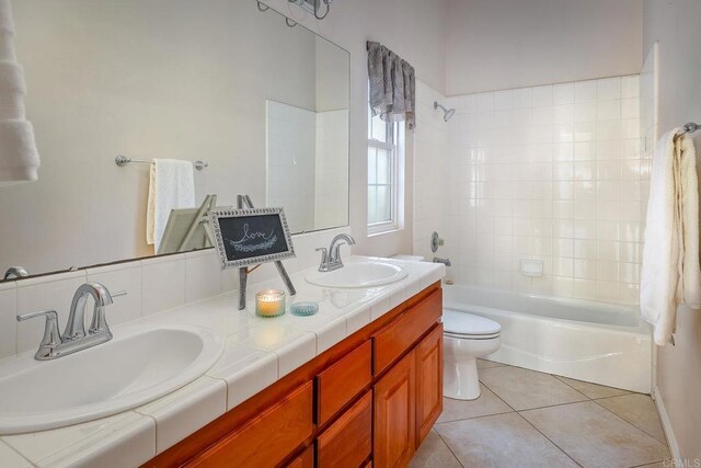 full bathroom with toilet, tile patterned flooring, tiled shower / bath, and vanity