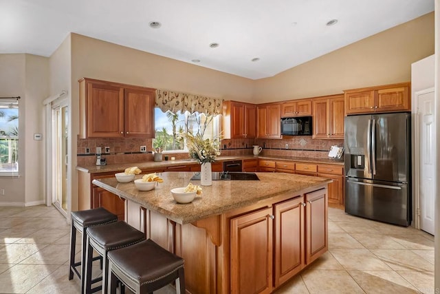 kitchen with light tile patterned flooring, a kitchen island, vaulted ceiling, and black appliances