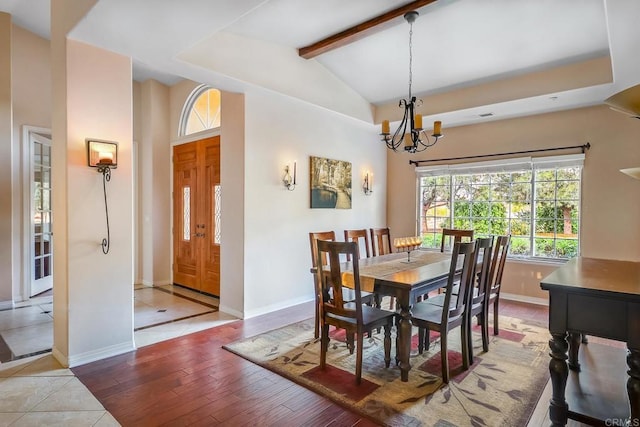 dining space featuring lofted ceiling with beams, wood-type flooring, and a notable chandelier